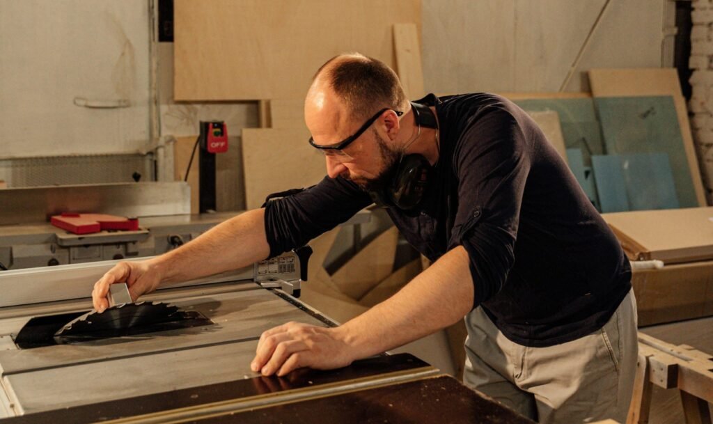 A craftsman operating machinery in a woodworking workshop.